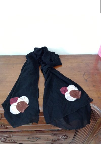 Black chiffon hijab featuring circular fabric floral appliques in maroon, cream, and brown at the ends.