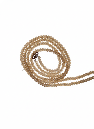 A detailed view of a necklace chain made from small, faceted champagne-colored crystal glass beads, shown coiled against a white background with a dark metal hook clasp.