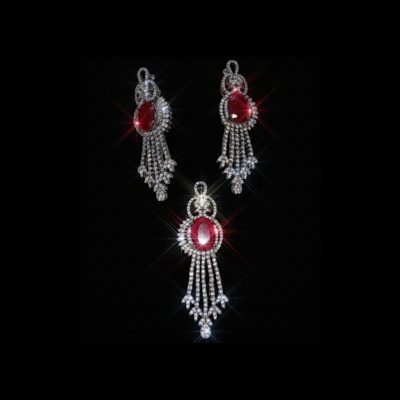 A sparkling jewelry set featuring a pendant and earrings with large oval red rubies surrounded by shimmering diamonds on a black background.