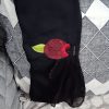 Close-up shot of an abaya sleeve cuff showing a maroon fabric flower with a green leaf and stone embellishments.