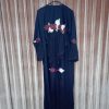 Rear view of a black abaya on a hanger, highlighting the ruffled back detailing and floral applique work.