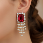A close-up of a model wearing a large emerald-cut ruby earring surrounded by diamonds with a cascading diamond fringe.