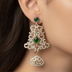 Close-up of antique style imitation chandelier earrings with green stone and crystal detailing worn on ear