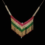 V-shaped fringe statement necklace crafted with rows of red, emerald green, and clear stones on a deep black background.
