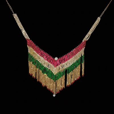 V-shaped fringe statement necklace crafted with rows of red, emerald green, and clear stones on a deep black background.