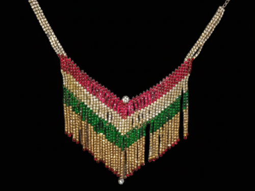 V-shaped fringe statement necklace crafted with rows of red, emerald green, and clear stones on a deep black background.