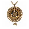 Detailed close-up of a circular gold sunburst pendant featuring an intricate flower center with black and amber gemstones on a beaded chain.