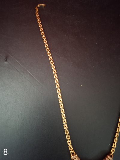 নেকলেসের পেছনের চেইন এবং হুক বা লকের অংশটি স্পষ্ট দেখা যাচ্ছে, যা একটি নিখুঁত সোনালি ফিনিশিং নির্দেশ করে।