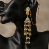 A side-profile view of a black jewelry mannequin wearing a tiered gold Jhumka earring. The image highlights the craftsmanship of the cascading chains and the way the ear chain drapes behind the ear.